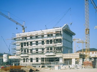 Baustelle von Mehrfamilienhaus mit Gerüst und 2 Kränen