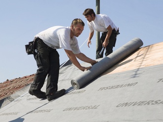 Dachdecker rollen Dachpappe auf Dach aus