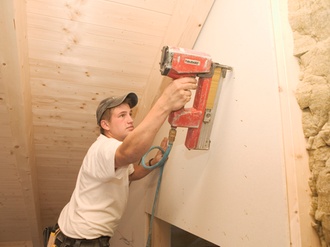 Handwerker befestigt mit Tacker Daemmmaterial bei Hausbau