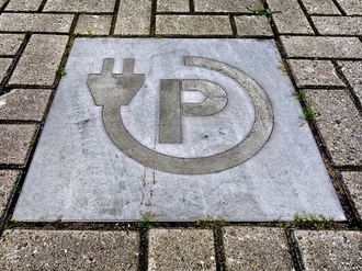 E-Ladesäule Icon in Pflastersteinen auf Parkplatz eingelegt