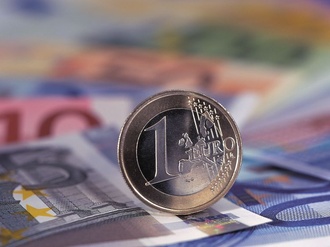 Euromünze rollt auf Scheinen Geld