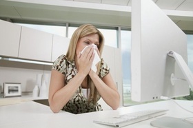 Frau im Büro putzt sich die Nase