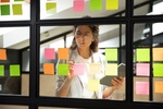 Businesswoman creates priority to-do list standing behind glass wall writes fresh ideas interesting