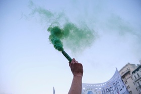 Buenos Aires, Argentina; Sept 24, 2021: Global Climate Strike, arm raising a green smoke flare as pa