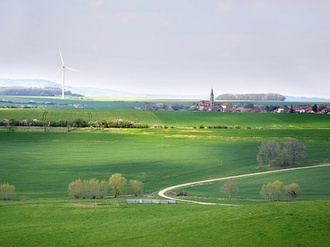 Große Freifläche mit kleinem Dorf und Windrad