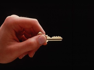 Hand mit Schlüssel vor dunklem Hintergrund