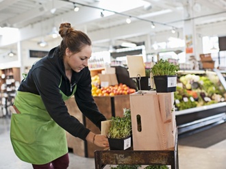 Junge erwachsene Mitarbeiterin sortiert Waren im Supermarkt