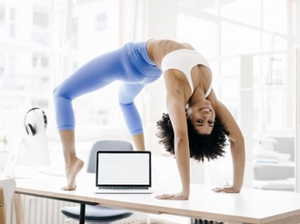 junge Frau macht Yoga auf ihrem Schreibtisch