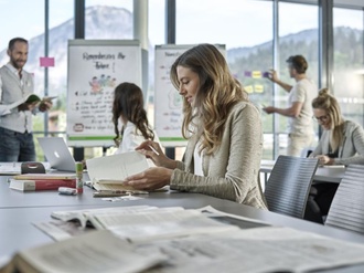 junge Mitarbeiterin blättert während Seminars in Unterlagen