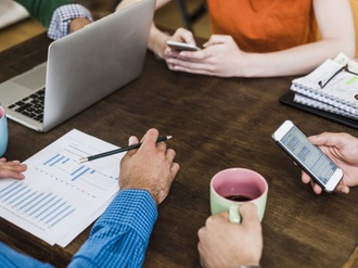 Colleagues at table with cell phones, laptop and document