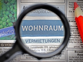 Lupe und Rotstift über der Zeitungsrubrik Wohnungen