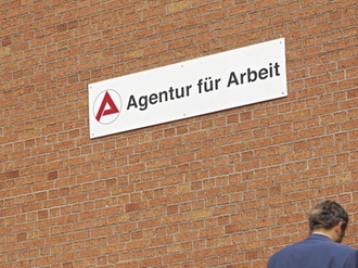 Mann sitzt ratlos vor Agentur fuer Arbeit