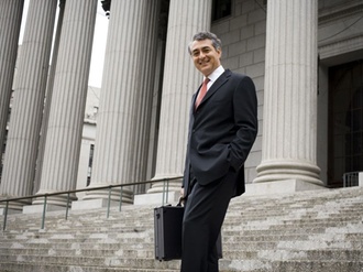 Low angle view of a male lawyer standing on the steps of a courthouse and smiling