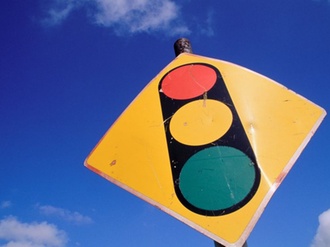 Schild mit Ampelwarnung vor blauem Himmel