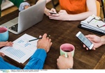 Colleagues at table with cell phones, laptop and document