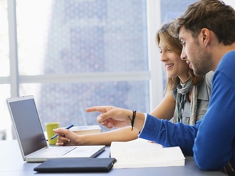 Student und Studentin sitzen vor Laptop und Bücher