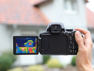 Thermografie Hand mit Kamera vor Wohnhaus