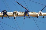 Team of sailors working together high at a yard of a huge sailing ship.