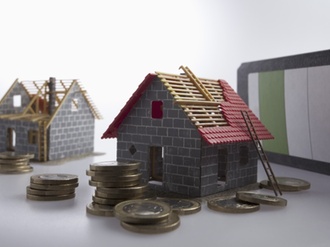 Two partially constructed models of a house with piles of European Union coins around them --- Image